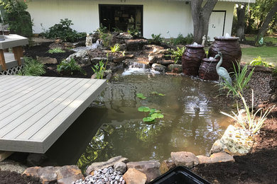 Diseño de jardín asiático grande en patio trasero con estanque y exposición parcial al sol