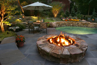 Imagen de jardín clásico grande en patio trasero con brasero y adoquines de piedra natural