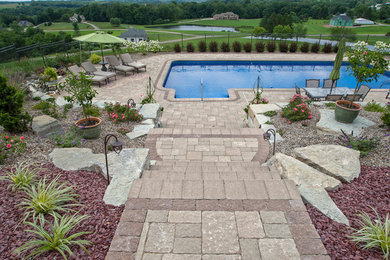 Large traditional sloped full sun garden for summer in Columbus with an outdoor sport court, a retaining wall and brick paving.