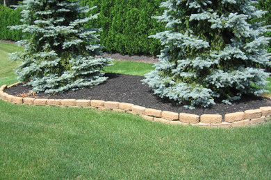 This is an example of a mid-sized full sun side yard stone retaining wall landscape in Cleveland.
