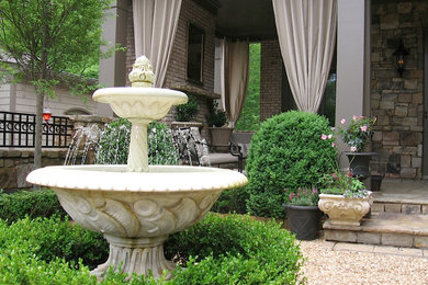 Ejemplo de jardín tradicional grande en patio trasero con jardín francés, fuente y adoquines de piedra natural