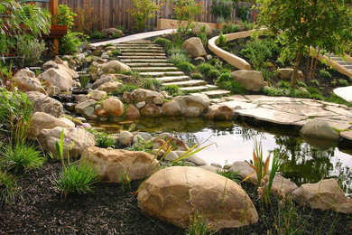 Imagen de jardín clásico renovado grande en patio trasero con jardín francés, estanque, exposición parcial al sol y adoquines de piedra natural