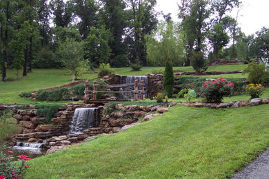 Inspiration for a traditional backyard stone water fountain landscape in Other.