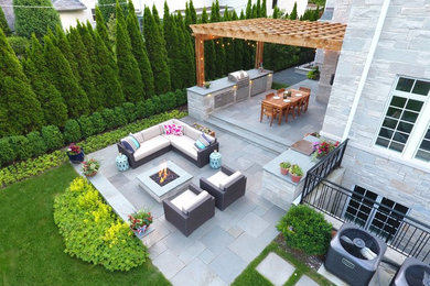 Patio - large contemporary backyard stone patio idea in Chicago with a fire pit