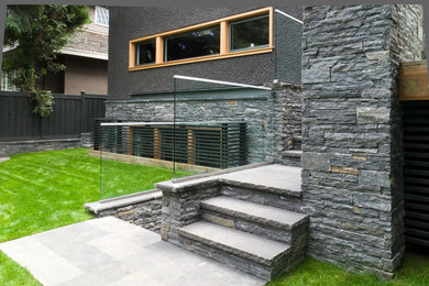 Imagen de jardín de estilo americano de tamaño medio en patio trasero con exposición total al sol y adoquines de piedra natural