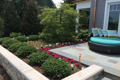 Imagen de jardín contemporáneo de tamaño medio en verano en patio trasero con jardín francés, muro de contención, exposición total al sol y adoquines de hormigón