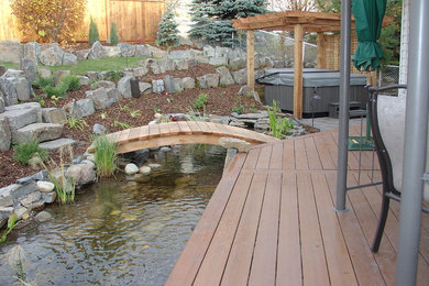Inspiration for a large contemporary partial sun backyard formal garden in Calgary with decking for winter.