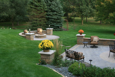 This is an example of a mid-sized traditional full sun backyard brick landscaping with a fire pit.