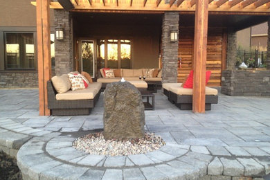 Cette photo montre une très grande terrasse arrière chic avec un foyer extérieur et des pavés en pierre naturelle.