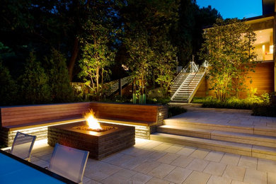 This is an example of a large contemporary backyard stone landscaping in Boston with a fire pit.