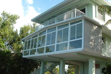 Imagen de acceso privado tropical grande en verano en patio delantero con exposición total al sol y adoquines de ladrillo