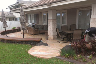 Medium sized world-inspired back partial sun garden in Hawaii with a retaining wall and natural stone paving.