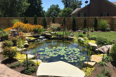 Ejemplo de jardín clásico grande en verano en patio trasero con jardín francés, estanque, exposición parcial al sol y adoquines de piedra natural