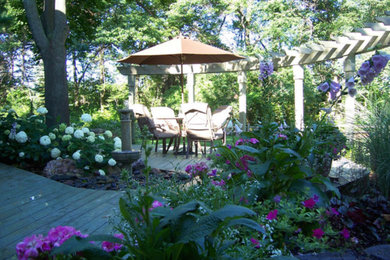 This is an example of a large contemporary shade backyard water fountain landscape in Detroit with decking.