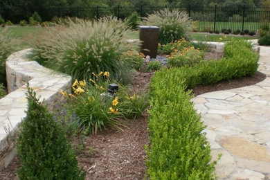 Immagine di un grande giardino classico esposto in pieno sole dietro casa in estate con un muro di contenimento e pavimentazioni in pietra naturale