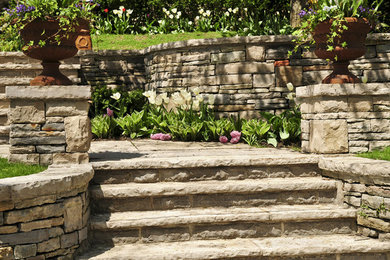 Inspiration for a mid-sized traditional full sun backyard stone landscaping.