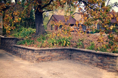 Modelo de acceso privado rústico de tamaño medio en verano en patio delantero con muro de contención, exposición parcial al sol y adoquines de piedra natural