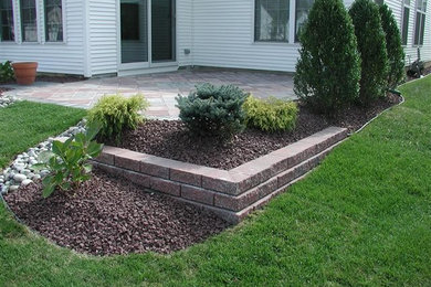Photo of a mid-sized partial sun backyard brick retaining wall landscape in New York.