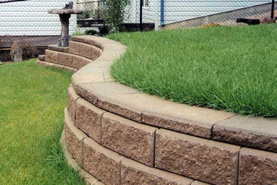 Design ideas for a mid-sized full sun backyard concrete paver retaining wall landscape in Calgary.