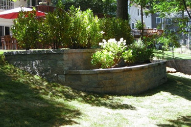 Inspiration for a mid-sized traditional partial sun backyard stone retaining wall landscape in New York.