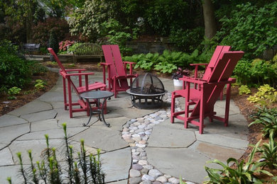 This is an example of a medium sized bohemian back patio in DC Metro with a fire feature and natural stone paving.