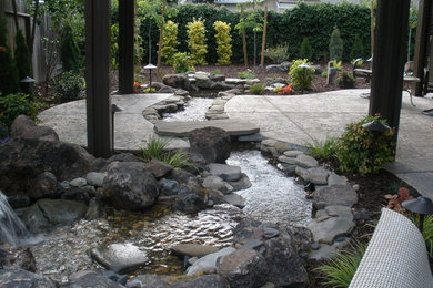 Ejemplo de jardín de estilo americano grande en patio trasero con jardín francés, fuente, exposición parcial al sol y adoquines de hormigón