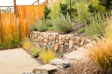 This is an example of a large traditional full sun backyard gravel retaining wall landscape in Other.
