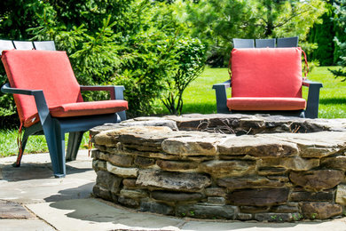 Design ideas for a rustic backyard stone landscaping in Chicago with a fire pit.