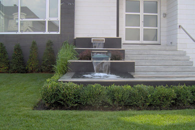 Diseño de jardín en patio delantero con fuente y adoquines de hormigón