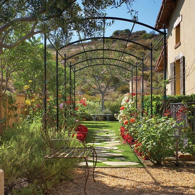 This is an example of a mid-sized mediterranean partial sun side yard stone landscaping in Orange County for spring.