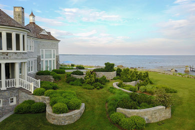 This is an example of an expansive modern back full sun garden for summer in Other with a retaining wall and natural stone paving.