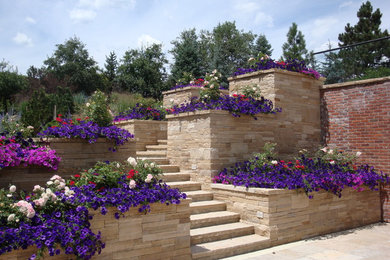 Imagen de jardín contemporáneo de tamaño medio en verano en patio trasero con exposición total al sol, adoquines de piedra natural y muro de contención