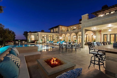 This is an example of a huge mediterranean full sun backyard stone landscaping in Orange County with a fire pit.