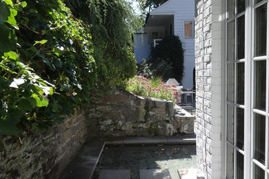 Diseño de jardín tradicional pequeño en patio trasero con fuente, exposición reducida al sol y adoquines de piedra natural