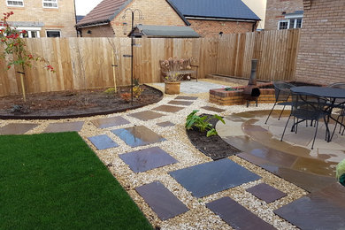 Medium sized back garden in Other with a fire feature and gravel.