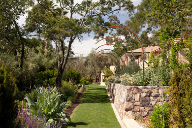 Diseño de jardín clásico de tamaño medio en patio trasero con jardín francés, muro de contención y exposición parcial al sol
