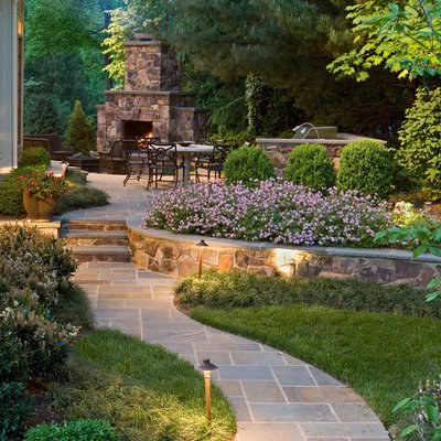 Photo of a large traditional backyard stone landscaping in DC Metro with a fireplace.