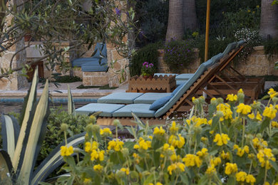Modelo de jardín mediterráneo de tamaño medio en patio trasero con jardín francés, fuente, exposición total al sol y adoquines de hormigón