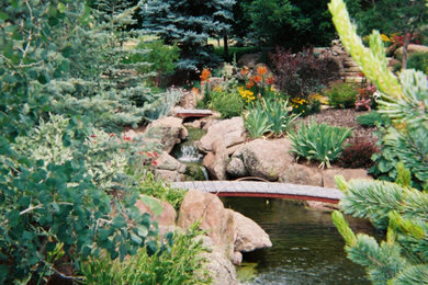 Bild på en stor funkis trädgård framför huset, med en fontän och naturstensplattor