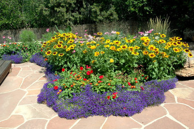 Imagen de jardín de estilo americano de tamaño medio en verano en patio trasero con exposición total al sol, jardín francés y adoquines de piedra natural
