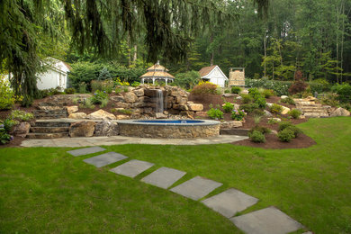 Cette image montre un grand jardin arrière traditionnel avec un point d'eau, une exposition ensoleillée et des pavés en pierre naturelle.