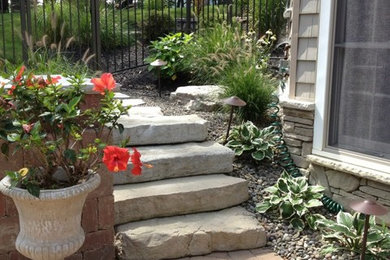 Photo of a mid-sized full sun backyard stone retaining wall landscape in New York.