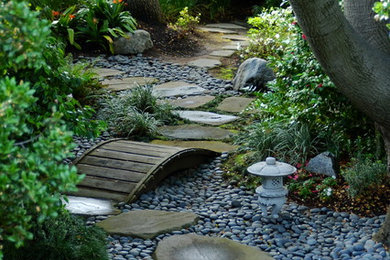 This is an example of a traditional shade backyard river rock water fountain landscape in San Francisco.