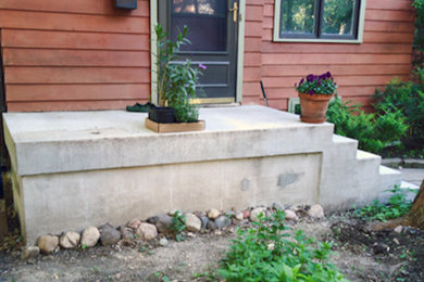 Ejemplo de jardín tradicional en patio delantero con muro de contención y adoquines de hormigón