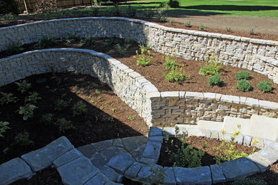 Design ideas for a mid-sized traditional partial sun backyard stone landscaping in Other for summer.