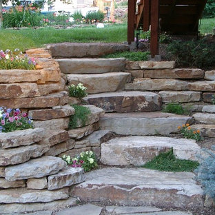 Photo of a large traditional shade backyard stone retaining wall landscape in New York.