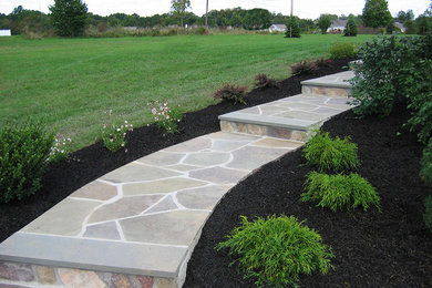 Design ideas for a large traditional full sun backyard stone landscaping in New York for spring.