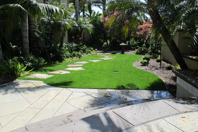 Immagine di un giardino tropicale di medie dimensioni e dietro casa con un ingresso o sentiero e pavimentazioni in pietra naturale