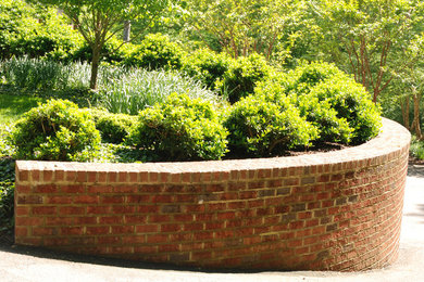 Modelo de jardín tradicional en ladera con muro de contención y adoquines de hormigón