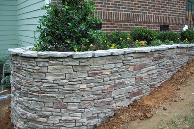 This is an example of a medium sized classic front full sun garden for spring in New York with a retaining wall.